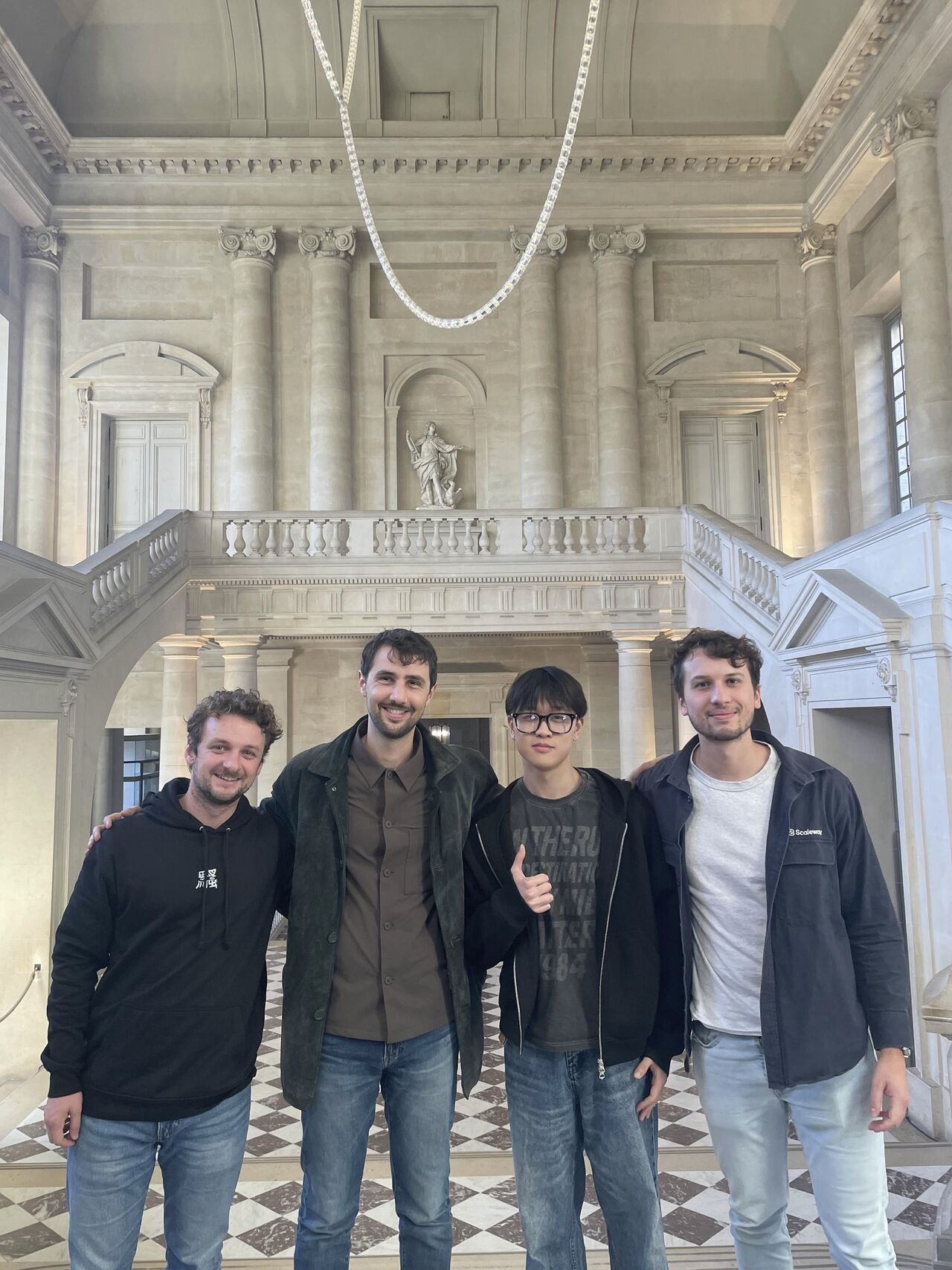 Team standing in front of a grand staircase at Versailles